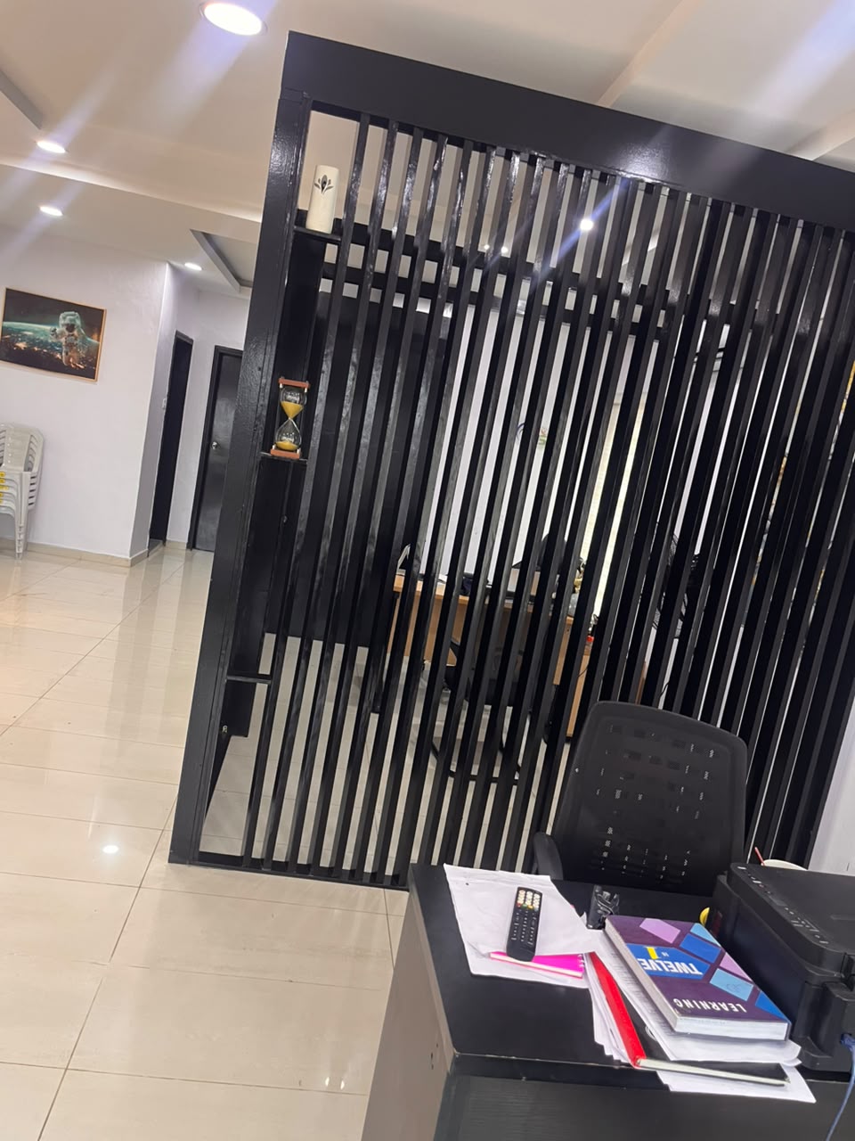 Black slatted divider separating the reception area from an office workspace