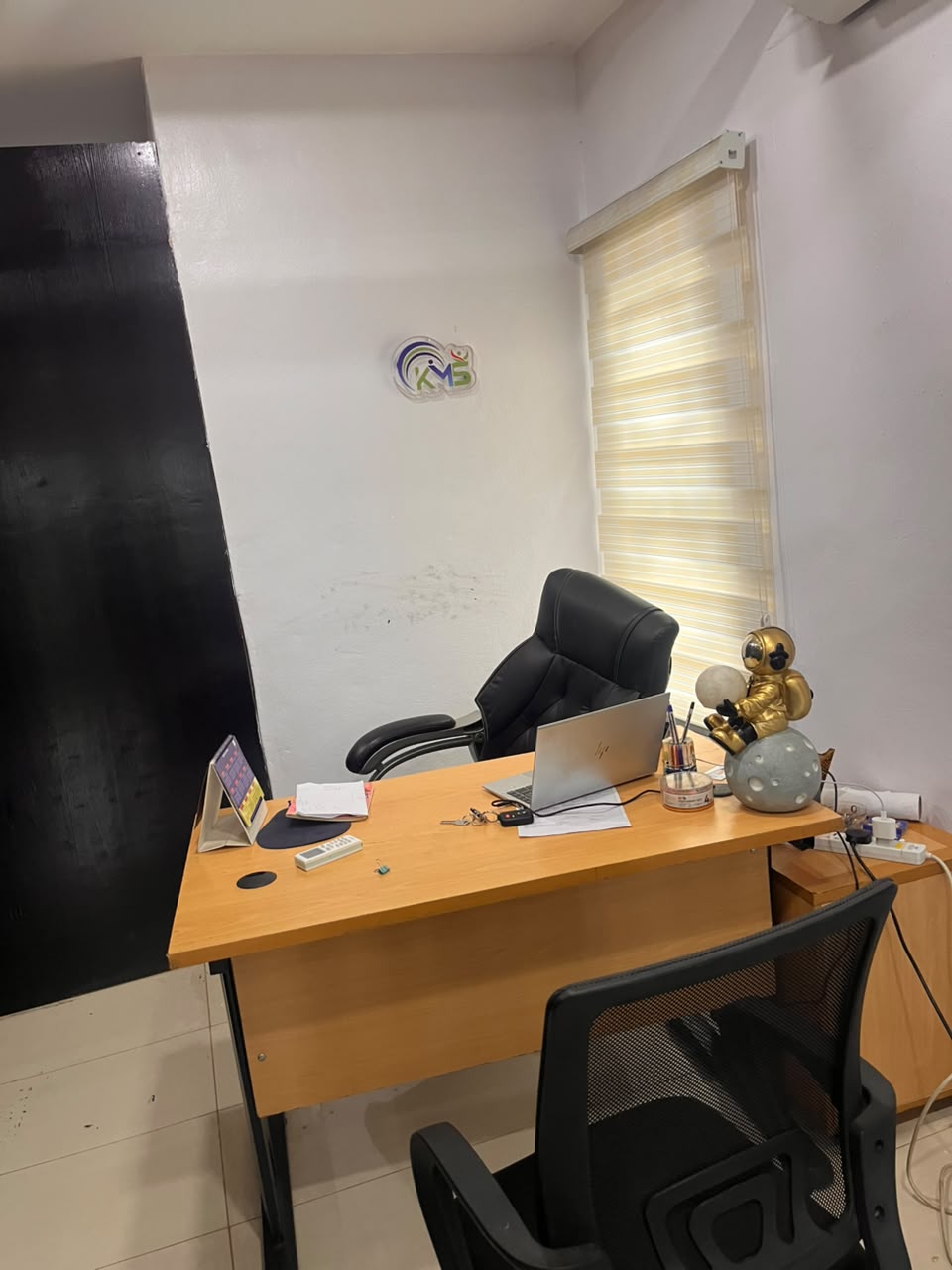 A manager's office with a desk, laptop and window blinds