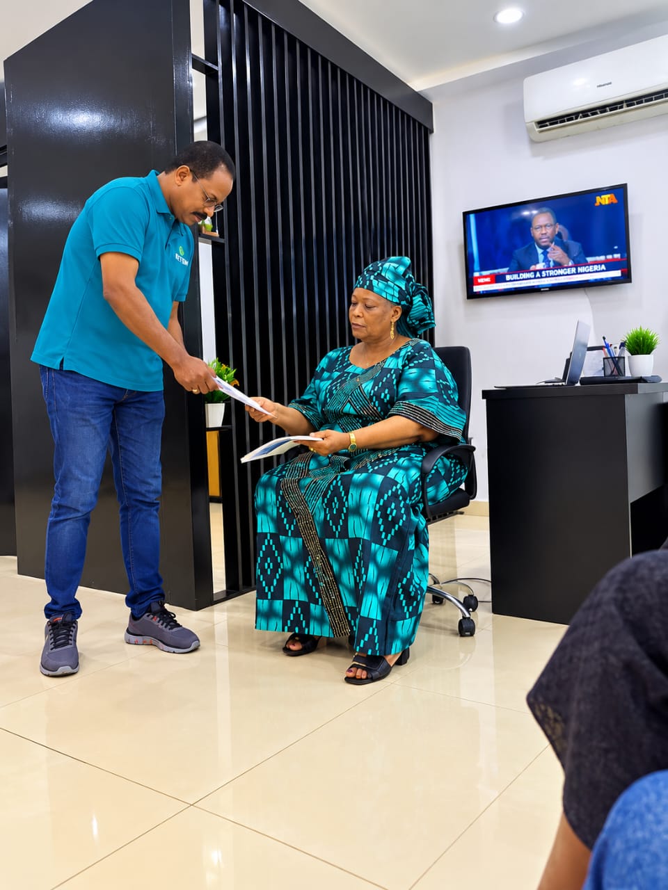 A staff member handing documents to a seated visitor at the KETBIM reception
