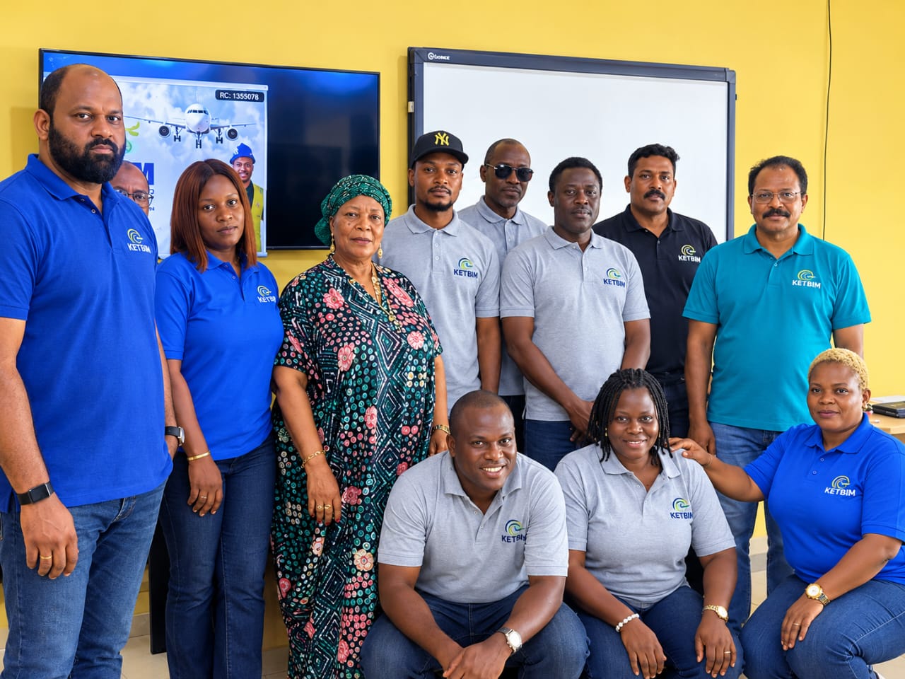 The KETBIM team in company polo shirts posing together in front of a presentation screen